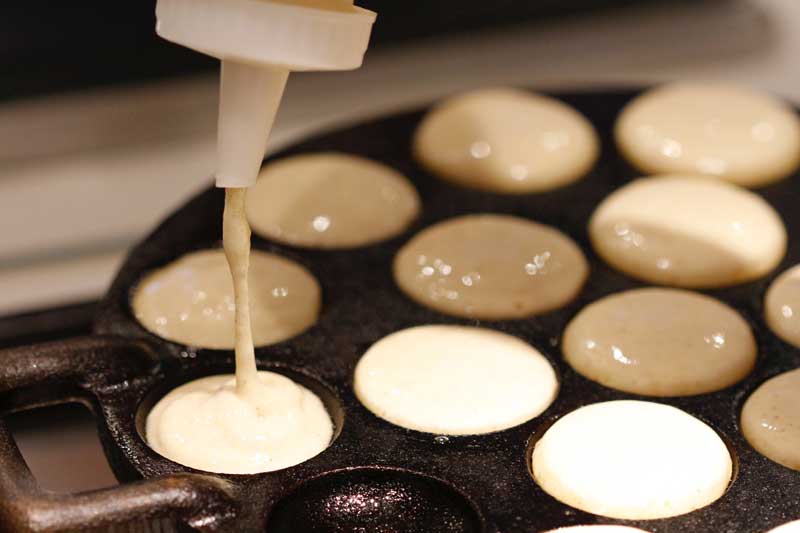 A squeeze bottle will give you a better control over the amount of poffertjes batter as well as precision